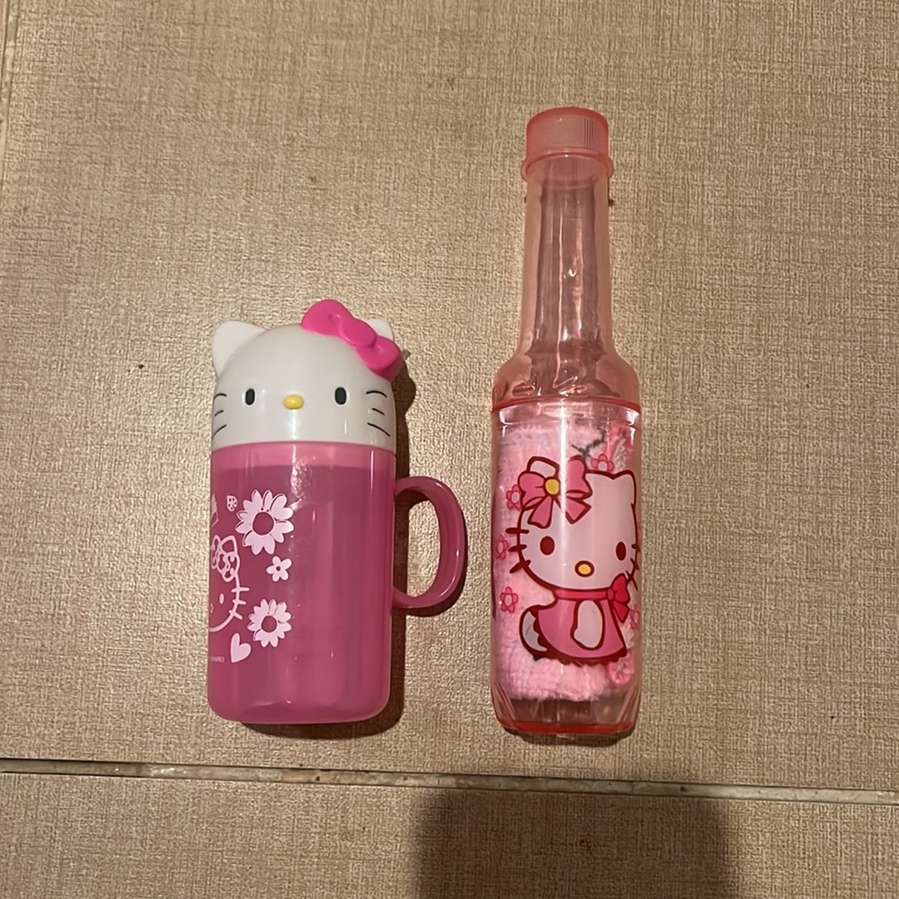 2 Hello kitty cups. One with a toothbrush and one with a towel
